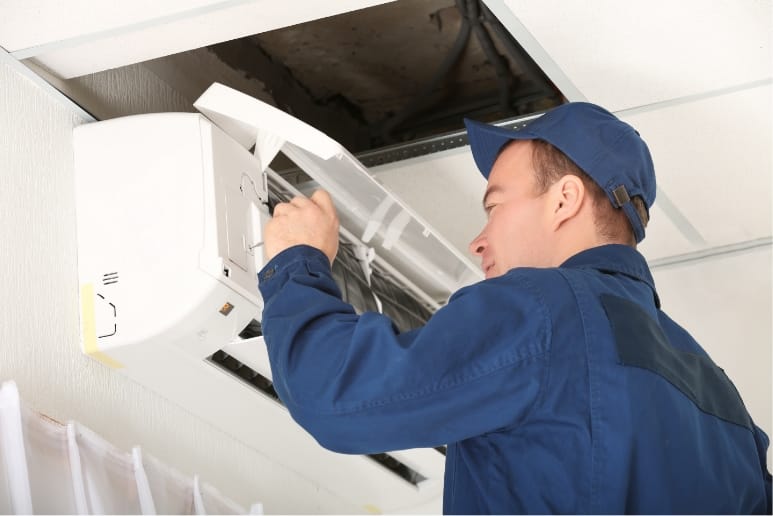 写真:作業着を着た男性がエアコンカバーを開けている