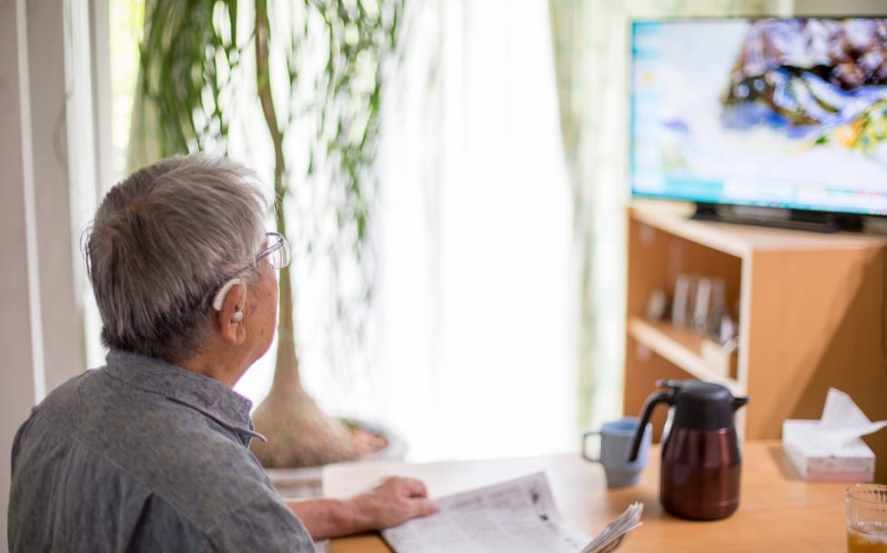 写真:補聴器をつけてテレビを見ている高齢者