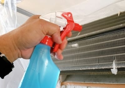写真:エアコンの内部に洗浄液を噴きかけている