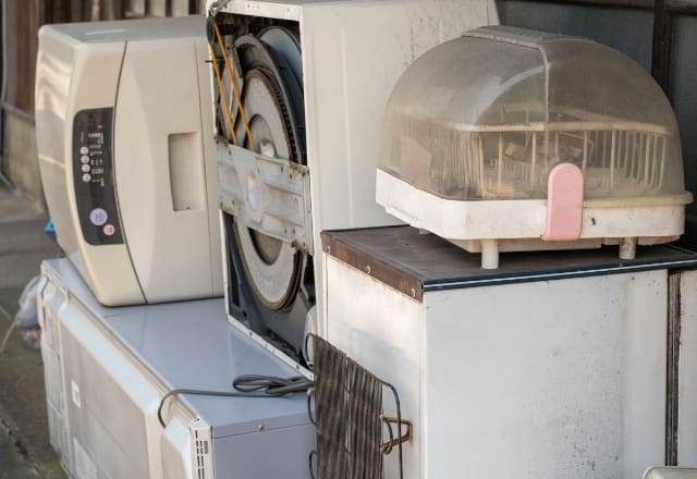 写真:古くなった家電が屋外で積まれている