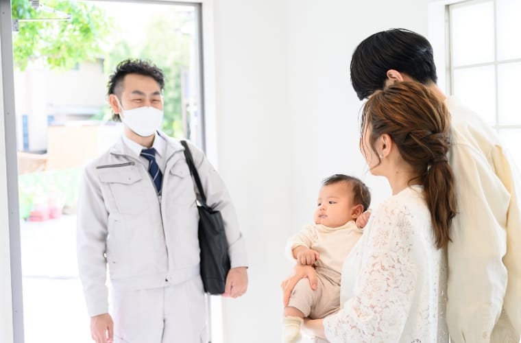 写真:玄関口に立つ作業員と、出迎える家族