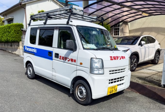 写真:三和デンキの車。白い車体に「三和デンキ(株)」の文字と、「Panasonic」のロゴが描かれている。